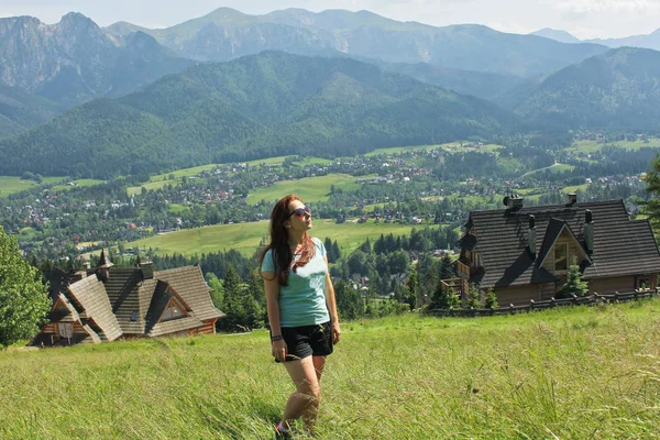 Woman enjoys hiking in the mountains and the sun. Girl traveles the Tatra National Park, Zakopane, Poland. Carpathian mountains on background.