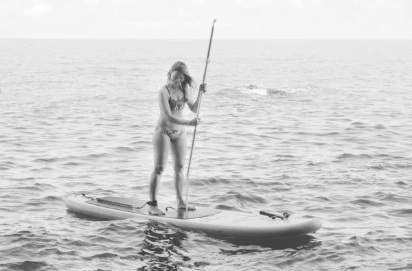 SUP Stand up paddle board. Black and white. Girl on summer holidays vacation lifestyle. Mtsvane Kontskhi Beach, Batumi, Georgia.