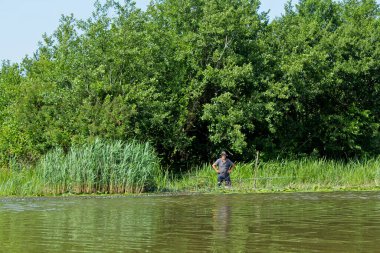 Kolkheti, Georgia - 23 Mayıs 2018. Kolkheti Ulusal Parkı 'nın bataklıklarında Churia Nehri manzarası. Balıkçı balık yakalıyor. Yaşlı bir adam sazlıkta duruyor..