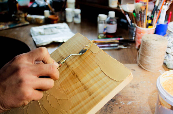 Putty knife in man's hand. The process of plastering in the workshop. Putty knife in man's hand. The process of plastering in the workshop. Preparation of boards before impregnation or painting.