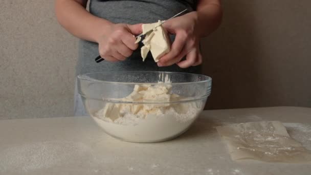 若い女性の手は キッチンナイフでバターを切断小麦粉とガラスボウルにそれを投げます 材料と準備段階 焼き菓子の作り方 — ストック動画