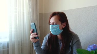 Kadın tıbbi ve koruyucu maskeyi çıkarıyor. Karantina sona erdi. Derin nefes alıyor ve gülümsüyor. Kız telefonda iyi haberler okudu. Salgının sonu.