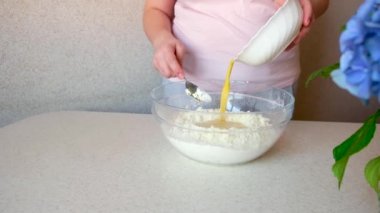 Kadın cam bir kaseye yumurta döker. Hamur yoğurmak. Malzemeler ve hamur hazırlama aşamaları. Aşçılık ve pastacılık adımları.