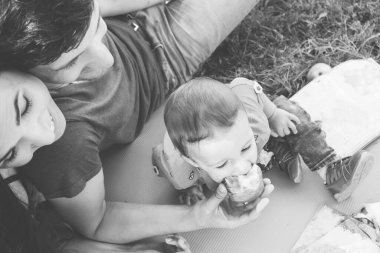 Küçük çocuk piknik zamanı babasının elinden bir elma yer. Yaşam tarzı. Mutlu bir ailenin samimi anları. Boş zaman, çocukluk, ebeveynlik ve birlikte hayattan zevk alma kavramı..