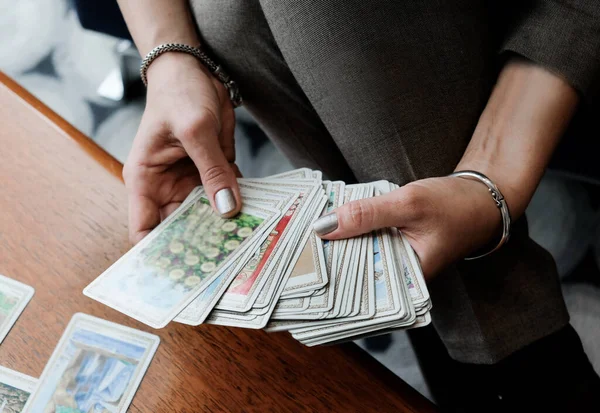 Kadınların eli Tarot kartlarını tahtada tutar. Kehanet, okült, ezoterik konsept.
