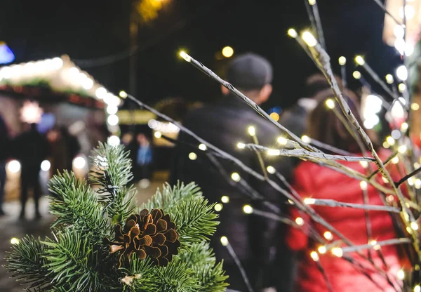 Kozalaklı fidan dalı. Dallar bir çelenkle süslenmiş. Yeni Yıl Fuarı ve kutlamaları Batumi, Gürcistan 'da. İnsanlar Noel festivaline bakıyor..