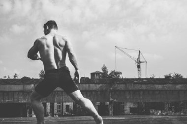 Çağdaş sanat dansı. Endüstriyel binada çıplak gövdeli genç dansçı. Siyah ve beyaz. Sokak şehir yaşam tarzı.