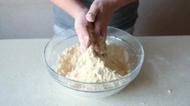 Kadın elleri tereyağı ve unu cam bir kasede karıştırır. Ev yapımı pişirme ve şekerleme..
