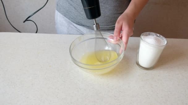 キッチンミキサーのホイップ卵の白とスプリンクル砂糖を持つ女性 電気ミキサーのビート 女の子の手はガラスボウルを保持します おいしい料理のためのチキン卵 — ストック動画