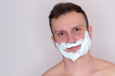 Tıraş genç adam portresi. Sakal beyaz köpük var. Ciddi ve yoğun biri. Beyaz arka plan üzerinde izole.