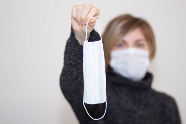 Sağlık maskesi takan hoş bir kız, düzgün görünüyor, beyaz bir arka planda izole edilmiş, grip salgını, toz alerjisi, virüs koruması. Şehirdeki hava kirliliği kavramı, yakın plan.