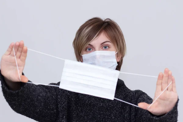 Sağlık maskesi takan hoş bir kız, düzgün görünüyor, beyaz bir arka planda izole edilmiş, grip salgını, toz alerjisi, virüs koruması. Şehirdeki hava kirliliği kavramı, yakın plan.