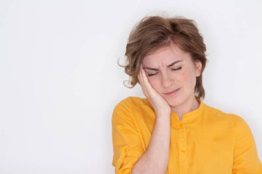 Mutsuz, bitkin, gözleri kapalı bir kız, şakaklarına yakından dokunuyor, yorgun bir kadın baş ağrısı ya da migrenden muzdarip, iyi hissetmiyor, uykusuzluk çekiyor, uykusuzluk çekiyor,