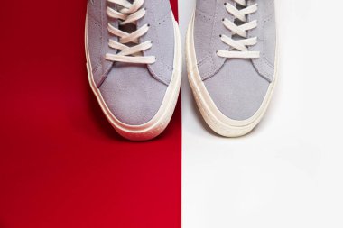 Kırmızı arka planda bir çift modaya uygun beyaz spor ayakkabı. Rahat ve şık ayakkabılar..