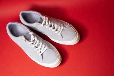 Kırmızı arka planda bir çift modaya uygun beyaz spor ayakkabı. Rahat ve şık ayakkabılar..