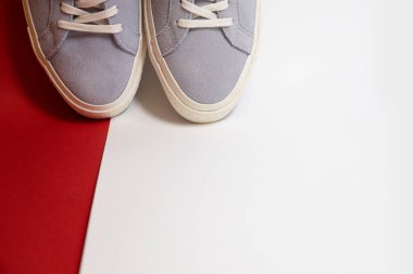 Kırmızı arka planda bir çift modaya uygun beyaz spor ayakkabı. Rahat ve şık ayakkabılar..