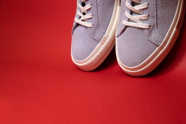 Kırmızı arka planda bir çift modaya uygun beyaz spor ayakkabı. Rahat ve şık ayakkabılar..