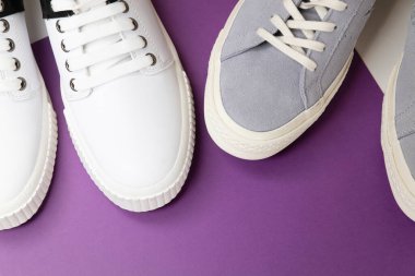 Beyaz ve mor arka planda beyaz ve gri erkek ayakkabıları. Düz kaşık, üst görünüm minimum arkaplan. Moda blogu veya dergisi konsepti.