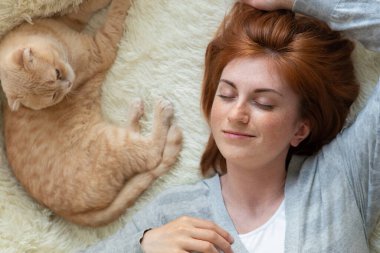 Sakin bir milenyum kadını kediyle rahat bir kanepede dinleniyor, meditasyon yapıyor ya da gündüz uykusunda, kaygısız tembel kız, nefes alıyor, stres hissetmiyor, kanepede dinleniyor.