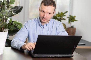 Başarılı bir girişimci, merkez ofiste çalışırken bilgisayarındaki bilgileri kontrol ederken memnuniyet içinde gülümserken, arkasında güneş parlıyor. Ev yalıtımı kavramı