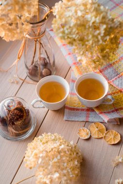 İki bardağı keten sarı peçeteye sıcak çay. Kurutulmuş ortanca, limon, kestane, tarçın. Yazıt için bir yer