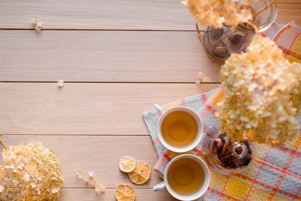 Due tazze di tè caldo su un tovagliolo di lino giallo. Ortensia secca, limone, castagna, cannella. Luogo di iscrizione — Foto Stock