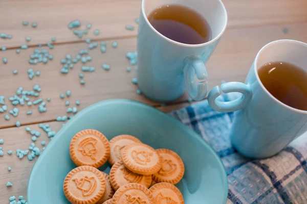 Dos tazas de té en una servilleta azul. Galletas sobre un plato azul sobre un fondo de madera — Foto de Stock