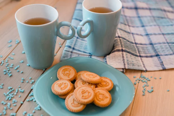 Дві чашки чаю на блакитній серветці. Печиво на синій тарілці на дерев'яному фоні — стокове фото