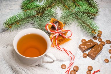 Bir fincan çay ile çikolata şekerleme, dokulu bir arka plan üzerinde bir çam ağacının dalını