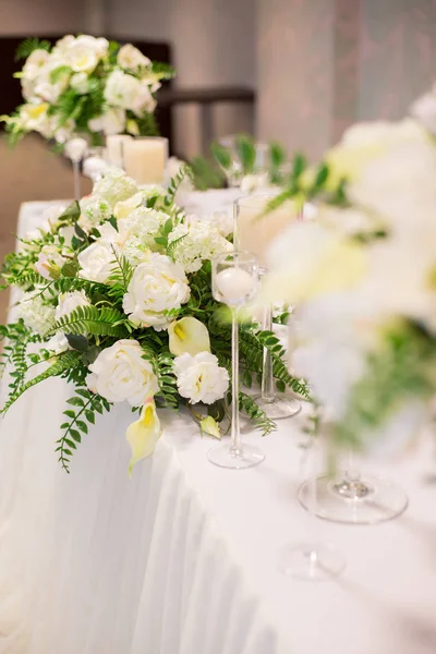 Hochzeitsdekor im Innenraum. weiße Blumen auf dem Tisch. Servieren der Tafel mit Kristallgläsern. — Stockfoto