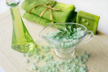 Spa kiti: sıvı sabun, deniz tuzu, yeşil havlu, taze çiçekler, beyaz bir arka plan üzerinde eski bir sarı peçete zeytin yaprağı