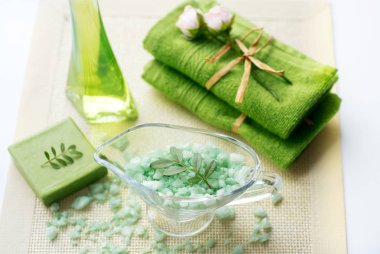 Spa kiti: sıvı sabun, deniz tuzu, yeşil havlu, taze çiçekler, beyaz bir arka plan üzerinde eski bir sarı peçete zeytin yaprağı