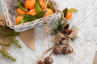 Yılbaşı yeni yıl kompozisyon mandalina çam kozalakları dokulu beyaz zemin üzerinde bir sepet içinde.