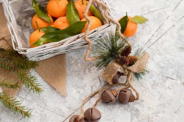 Yılbaşı yeni yıl kompozisyon mandalina çam kozalakları dokulu beyaz zemin üzerinde bir sepet içinde.