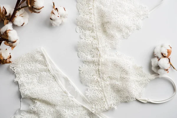 Conjunto de lingerie, bege com fitas brancas pretas. No fundo branco no fundo branco decorado com flores de algodão — Fotografia de Stock