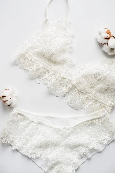 Conjunto de lencería, beige con cintas blancas negras. Sobre fondo blanco sobre fondo blanco decorado con flores de algodón — Foto de Stock