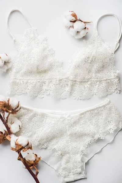 Satu set lingerie, beige dengan pita putih hitam. Pada latar belakang putih pada latar belakang putih dihiasi dengan bunga kapas — Stok Foto