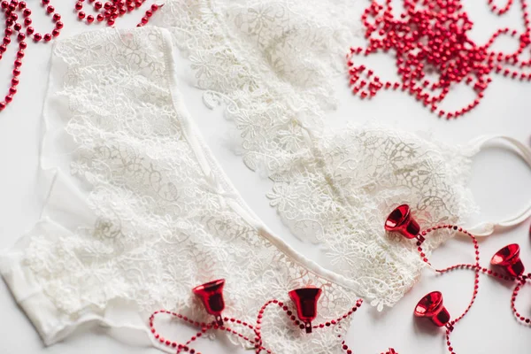 Ropa interior de Navidad, cuentas rojas, rama de un árbol de Navidad verde sobre un fondo blanco — Foto de Stock