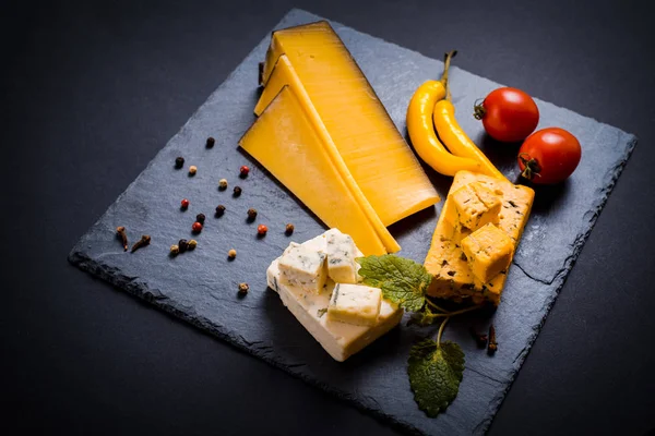 Placa de queso con queso azul, brie, queso duro de trufa con uvas, higos, peras, miel, galletas saladas, frutos secos y nueces en la mesa . — Foto de Stock