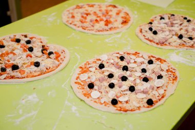 Masada kafede çeşitli malzemelerle pizza hazırlanması