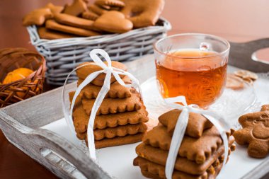 Gingerbread bir tepsi üzerinde sıcak çay ile. Zencefilli bisküvi ahşap bir masa üzerinde büyük bir set