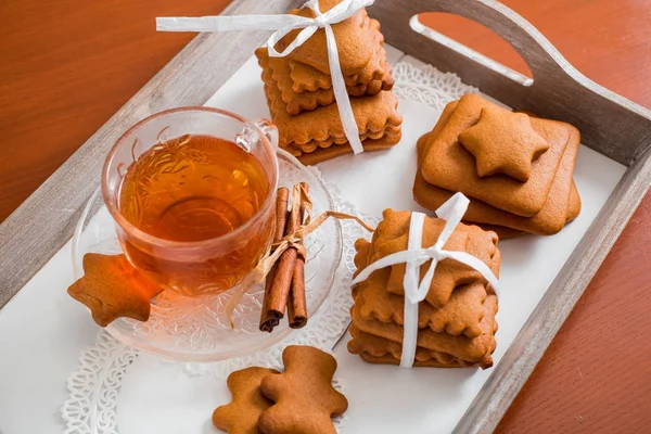 Gingerbread bir tepsi üzerinde sıcak çay ile. Zencefilli bisküvi ahşap bir masa üzerinde büyük bir set