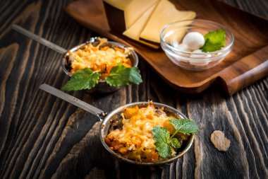 Mantar sıcak Yemeği, fırında tavuk bir peynir kabuk altında bir kremalı sos Beşamel içinde yeşil dekorasyonda karanlık bir arka plan üzerinde küçük seramik kaseler.