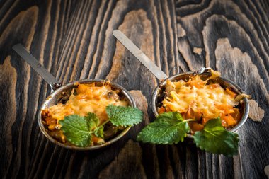 Mantar sıcak Yemeği, fırında tavuk bir peynir kabuk altında bir kremalı sos Beşamel içinde yeşil dekorasyonda karanlık bir arka plan üzerinde küçük seramik kaseler.