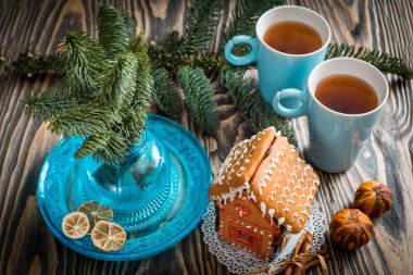 Ev yapımı Noel kurabiye evi bir tabloda görüntülenir. Noel ağacı ışıkları içinde belgili tanımlık geçmiş.