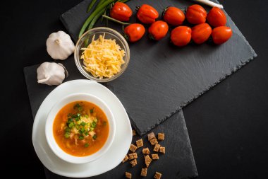 Domates gazpacho çorbası yeşil pesto sosu, tuz ve fesleğen kopya alanı ile eski siyah demir arka plan üzerinde seramik bardak. Sağlıklı beslenme kavramı.
