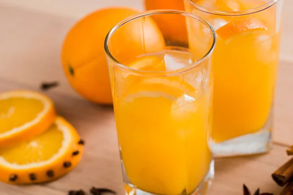 Fresh orange juice in the glass jar. Spices of cinnamon, cardamom, cloves. On a wooden background — Stock Photo, Image