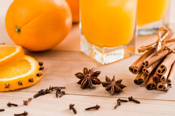 Verse jus d'orange in de glazen pot. Specerijen van kaneel, kardemom, kruidnagel. Op een houten achtergrond — Stockfoto