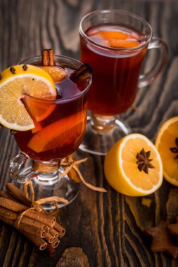 Sıcak baharatlı baharatlar ile mulled şarap ve turuncu. Limon, tarçın ve koyu ahşap arka plan üzerinde kakule.