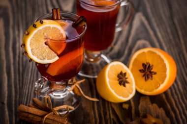 Sıcak baharatlı baharatlar ile mulled şarap ve turuncu. Limon, tarçın ve koyu ahşap arka plan üzerinde kakule.